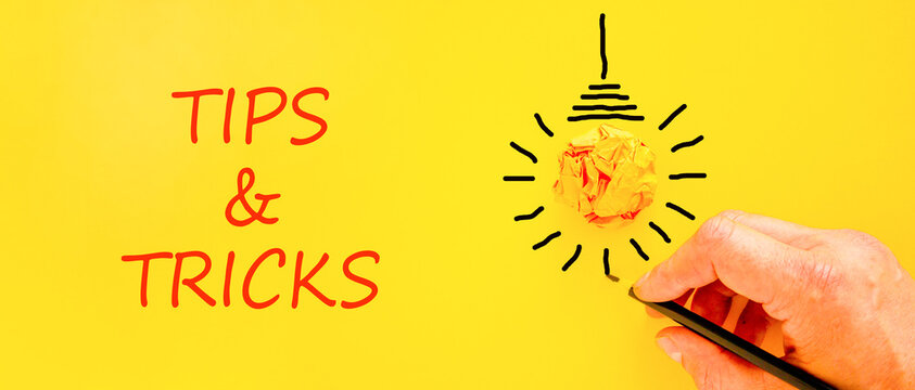 Tips and tricks words symbol. Concept words Tips and tricks on beautiful yellow paper. Beautiful yellow background. Businessman hand. Business tips and tricks motivational support concept. Copy space.