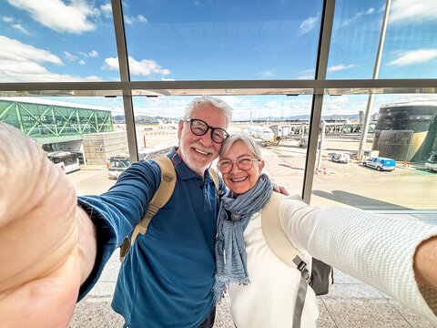 Happy senior couple taking an airport selfie before boarding a flight for travel and vacation