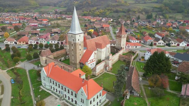 High angle view of the historic Mosna fortified church in Sibiu county. A beautiful 14th-century Gothic Saxon monument surrounded by defensive walls and towers in rural Transylvania, Romania.
