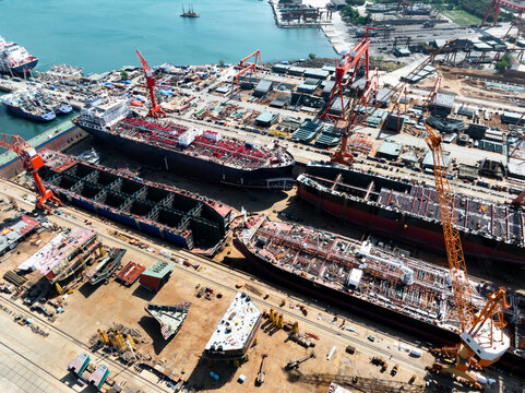 Aerial view of large ship construction site in shipyard with cranes and hull sections