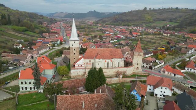 High angle view of the historic Mosna fortified church in Sibiu county. A beautiful 14th-century Gothic Saxon monument surrounded by defensive walls and towers in rural Transylvania, Romania.