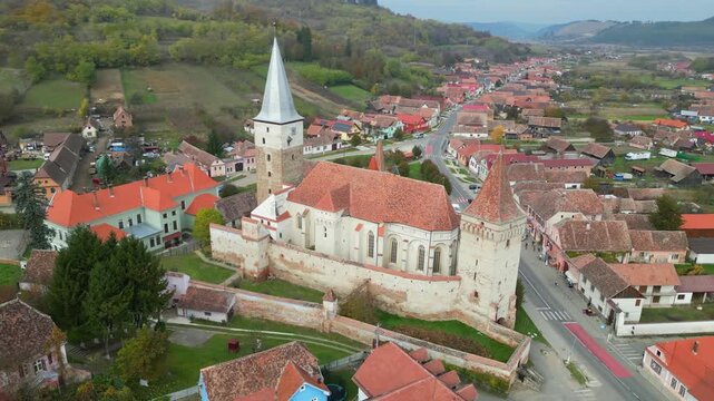 High angle view of the historic Mosna fortified church in Sibiu county. A beautiful 14th-century Gothic Saxon monument surrounded by defensive walls and towers in rural Transylvania, Romania.