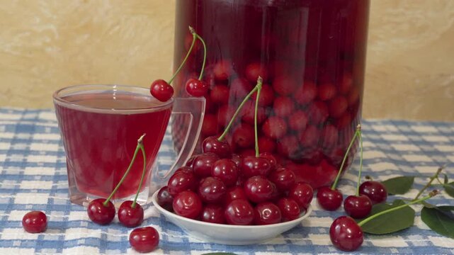 still life with homemade cherry compote and fresh berries, A large glass jar completely filled with cherry compote with whole berries. A glass cup with a rich red drink