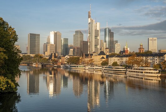 Excursion boats on the river bank, view over the Main, skyline reflected in the river, skyscrapers in the banking district in the morning light, Frankfurt am Main, Hesse, Germany