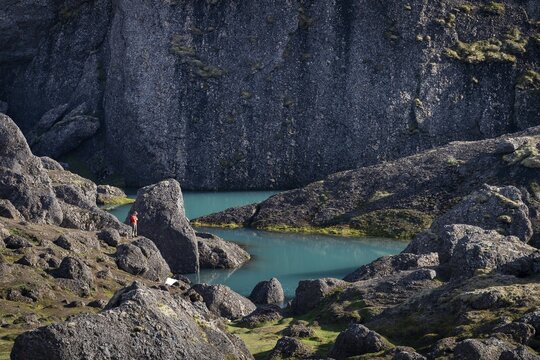 Man standing at turquoise water pool, St&oacute;rur&eth; landslide in Dyrfj&ouml;ll, Iceland