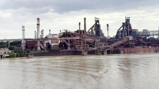 big steel meal with own berth in port. industrial landscape, coal and iron ore piles. smock and steam. production of steel.
