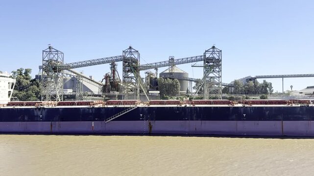 big bulk carrier ship moored alongside the berth of grain terminal. silo construction. loading pipes, bridges, towers, tanks.