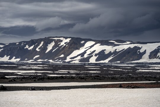 Snow-covered volcanic landscape with volcanic sand and petrified lava, crater of Askja volcano, Icelandic highlands, Iceland