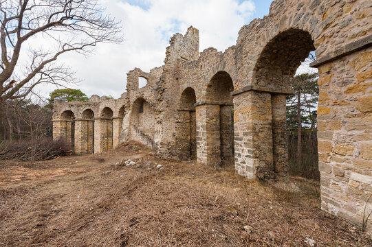 Romantic stone arcade folly ruin with arches in winter forest at Moedling Hauerhaus park