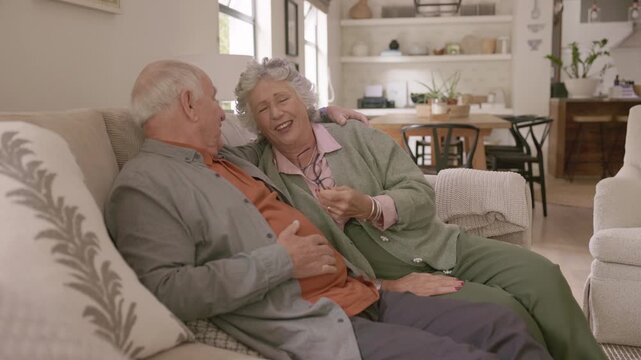 Joyful senior couple sitting on a couch having a conversation at home