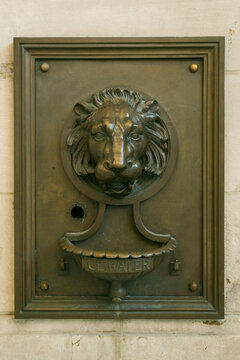 Lion head wall fountain detail on a historic facade