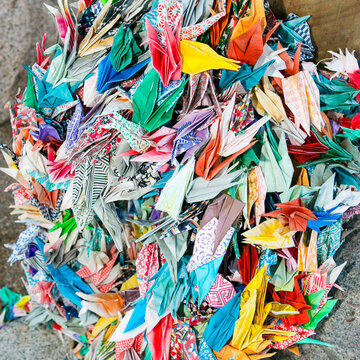 Colorful origami paper cranes in a bright pile
