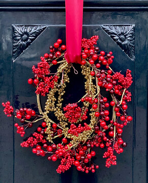 Red Christmas berry wreath on a dark paneled door