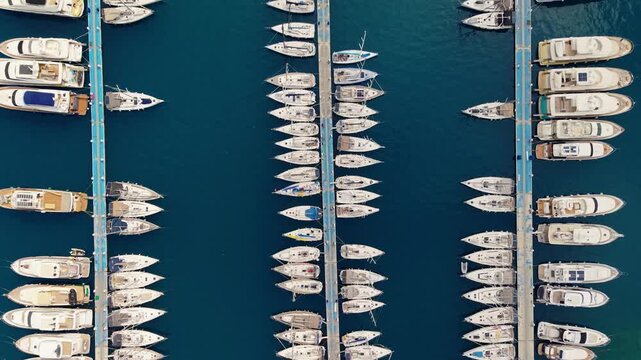 Aerial view of yachts boats and sailboats moored at marina piers along waterfront from top down Marmaris Turkey.