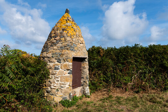 Lichen covered conical Breton stone shelter with wooden door in coastal heath Plougrescant