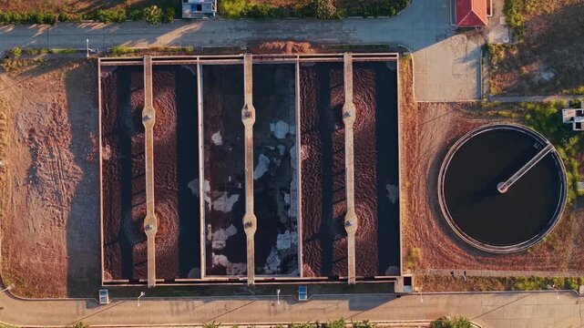 Aerial view wastewater treatment basins with rotating sludge and clarifier arm at treatment plant.