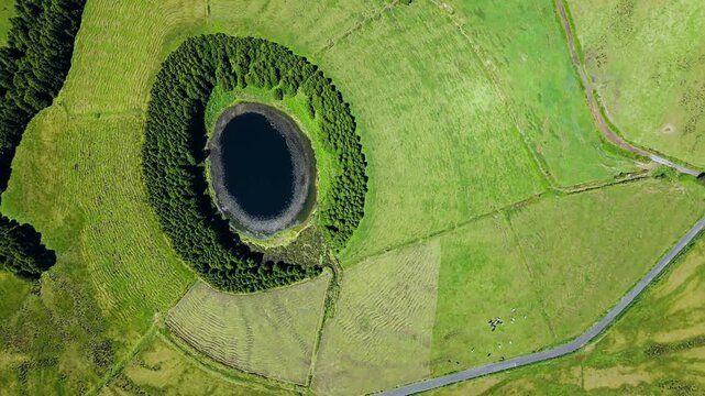Round Pau Pique crater lake surrounded by trees, Sao Miguel, Azores, Aerial view lush green landscape in Azores