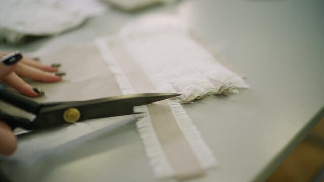 Close up of layered white and beige textile samples with frayed edges arranged on a fashion studio table