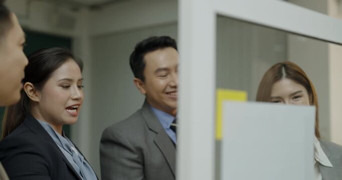 Business concept of 4k Resolution. Group of Asian businessmen helping brainstorm together and taking notes on mirrors, sticky notes, Planning economic strategies