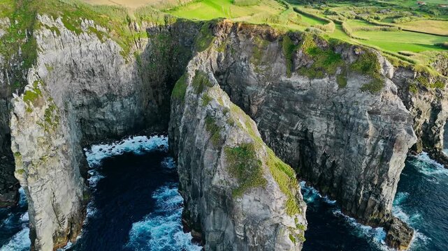 Steep drop-offs and layered volcanic rock formations along the coastline of Cape Cintrao at sunset, Azores