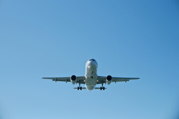 Fototapeta premium White passenger airplane climbing after takeoff against a clear blue sky. Travel concept