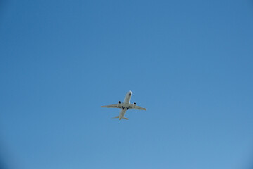 Obraz premium White passenger airplane climbing after takeoff against a clear blue sky. Travel concept