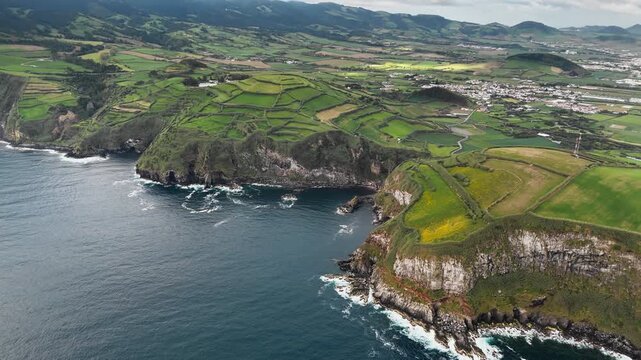 Agricultural patchwork landscape above rocky shore with Atlantic Ocean below, Azores Islands. Aerial view