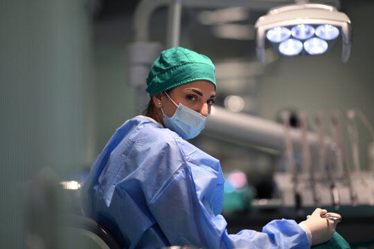 Female Dentist In Surgical Mask And Scrubs Looking Back In Modern Dental Clinic Operatory
