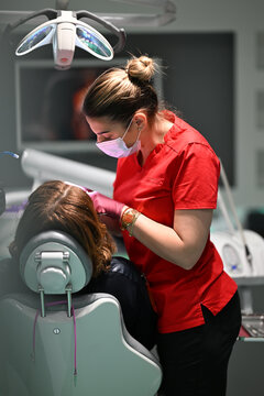 Female Dentist Examining Patient During Routine Checkup In Modern Dental Clinic Wearing Mask And Gloves
