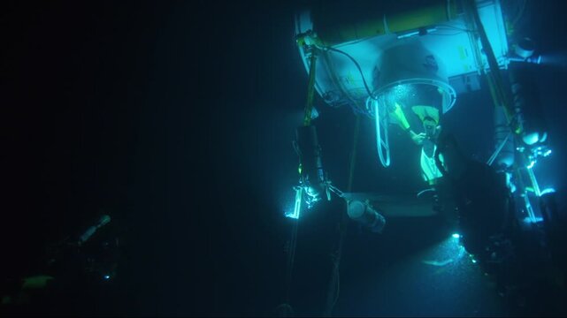 Saturation divers operating in the deep sea, exiting an underwater diving bell habitat