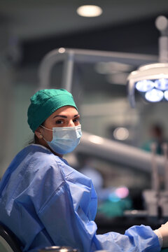 Female Surgeon In Surgical Mask And Scrubs Looking Back In Modern Operating Room