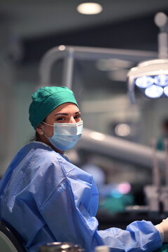 Female Dentist Wearing Surgical Mask and Scrubs in Modern Dental Clinic Smiling at Camera