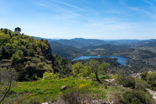 An expansive vista from a cliff edge overlooking the blue waters of the Siurana reservoir (Panta de Siurana) surrounded by the Prades Mountains in Catalonia.