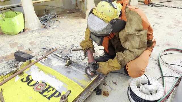 ship fitter make repairing of ship metal water tight door. after cutting damaged parts polishing metal by electrical grinder for weld new metal. sparks.