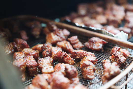 Delicious, tender pork belly cubes cooking on a pellet grill smoker. The meat medallions will be burnt ends when the smoke cook is finished. 