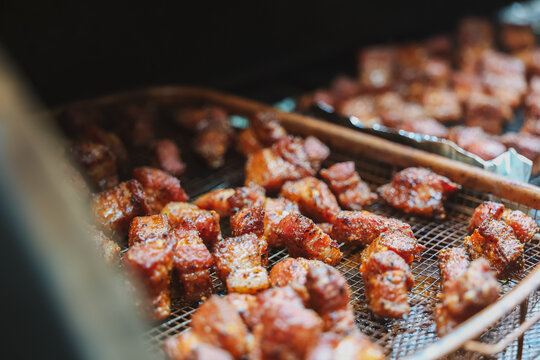 Delicious, tender pork belly cubes cooking on a pellet grill smoker. The meat medallions will be burnt ends when the smoke cook is finished. 