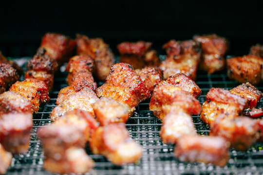 Delicious, tender pork belly cubes cooking on a pellet grill smoker. The meat medallions will be burnt ends when the smoke cook is finished. 