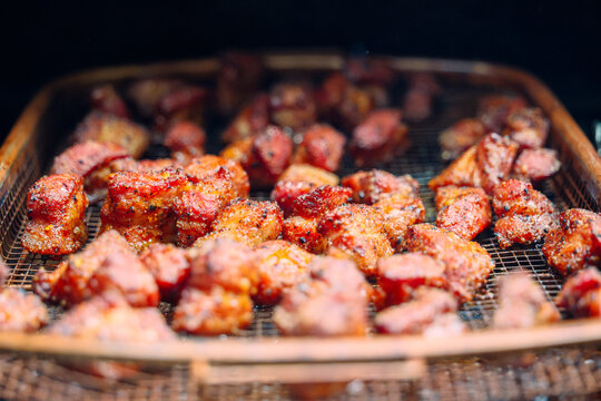 Delicious, tender pork belly cubes cooking on a pellet grill smoker. The meat medallions will be burnt ends when the smoke cook is finished. 