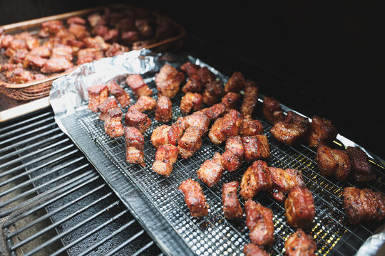 Delicious, tender pork belly cubes cooking on a pellet grill smoker. The meat medallions will be burnt ends when the smoke cook is finished. 