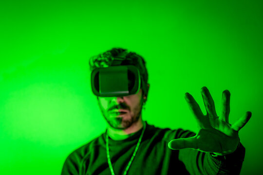 Man immersed in virtual reality experience reaching out in green light