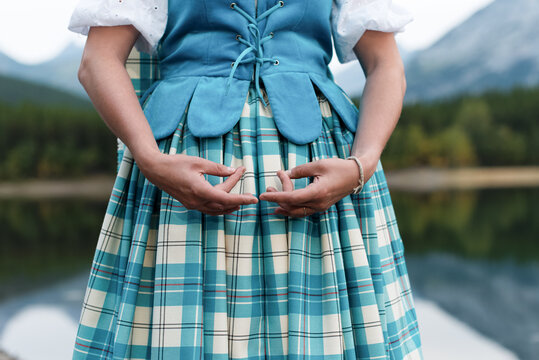 Highland dancer in blue Aboyne vest and tartan kilt with proper hand position by mountain lake
