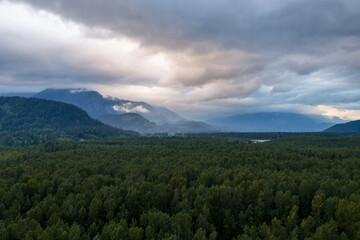 Fototapeta premium Misty Forest and Mountain Panorama Under Dramatic Clouds Near the Fraser River in Chilliwack, British Columbia
