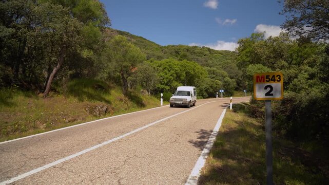 Carretera comarcal de la Comunidad de Madrid con varios coches circulando entre el paisaje rural y la vegetaci&oacute;n del entorno.