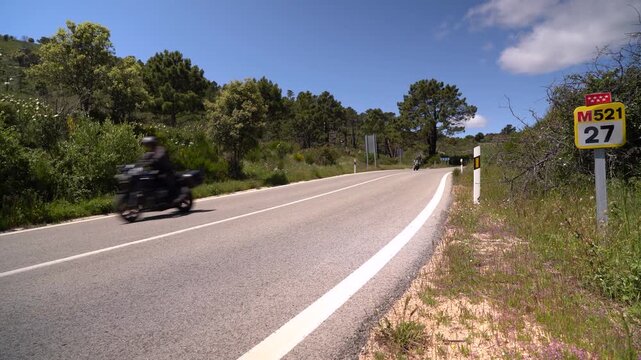 Carretera comarcal de la Comunidad de Madrid con varios coches circulando entre el paisaje rural y la vegetaci&oacute;n del entorno.