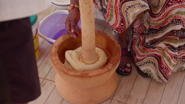 Ghanaian woman preparing traditional fufu in Accra, skillfully pounding cassava dough in wooden mortar with pestle, authentic African culinary traditions