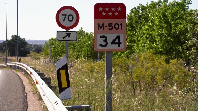 Carretera comarcal de la Comunidad de Madrid con coches circulando, se&ntilde;al de tr&aacute;fico y punto kilom&eacute;trico junto a la calzada.