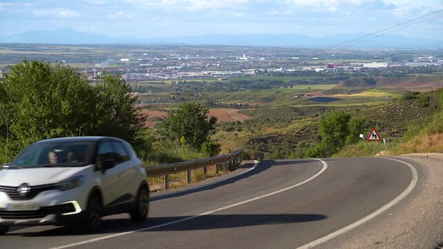 Carretera comarcal de Madrid con curvas pronunciadas y varios veh&iacute;culos circulando entre el paisaje rural de la Comunidad de Madrid.