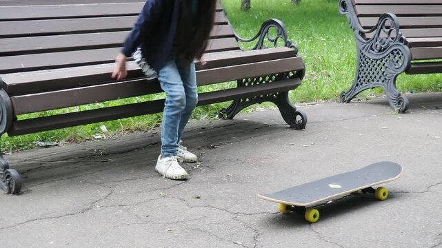Children playing active sports in a park. A girl learning to skateboard. A girl or child playing skateboarding or surfing outdoors in a park, engaging in extreme sports and protective knee pads