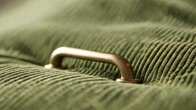 Matte brass handle resting on olive green corduroy fabric