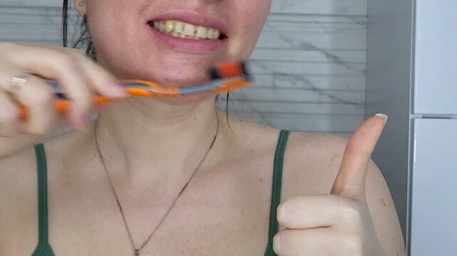 Detail of a woman brushing upper teeth, orthodontic oral hygiene and dental care routine indoors